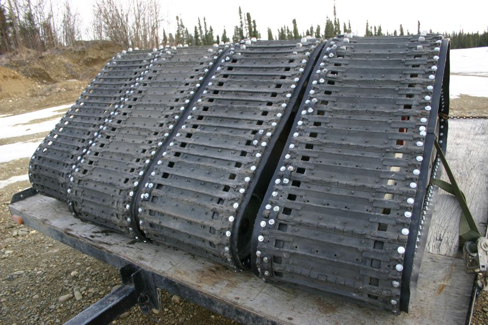 Three black snowmobile tracks on a trailer
