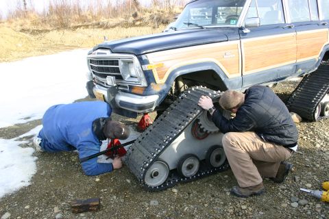 2003 Jeep TJ - Two people work on installing snow tracks onto a Jeep Grand Wagoneer.