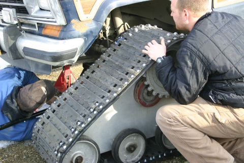 2003 Jeep TJ - A vehicle is being fitted with a snow track system, with two individuals assisting in the process.