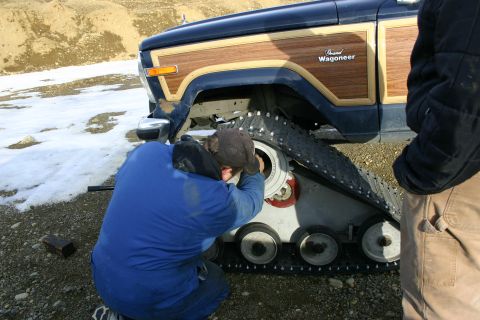2003 Jeep TJ - A Grand Wagoneer is modified with snow tracks in a snowy, outdoor environment.