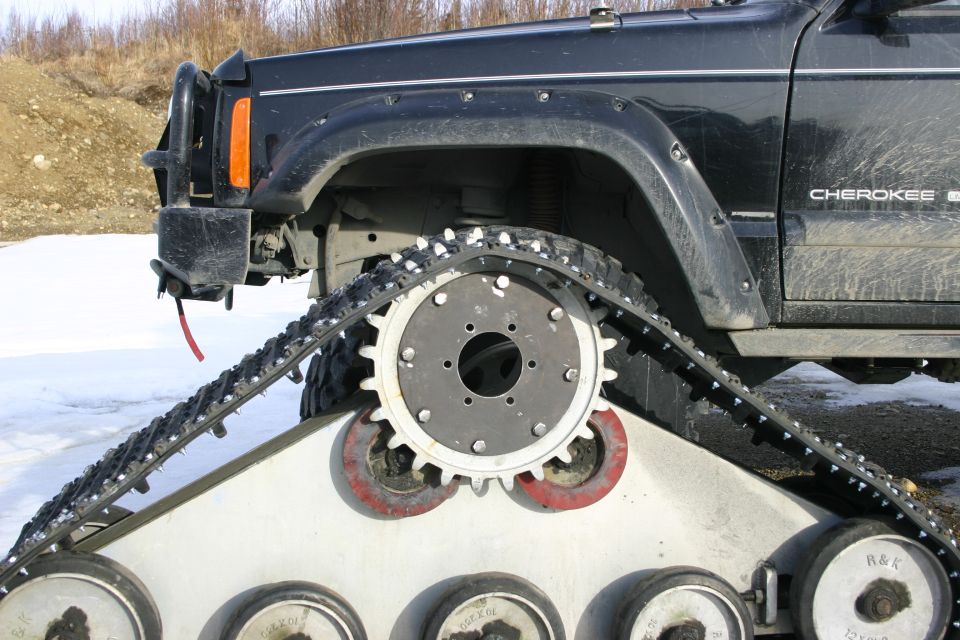 Side view of a black Jeep Cherokee with tracks instead of wheels