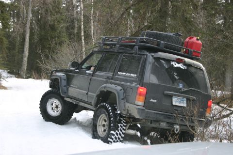 2003 Jeep TJ - A modified Jeep Cherokee XJ navigates a snowy trail, equipped for off-road adventure.