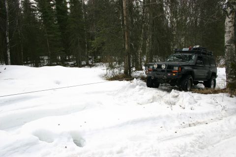 2003 Jeep TJ - A black Jeep Cherokee XJ navigates a snow-covered trail with a winch line extended.