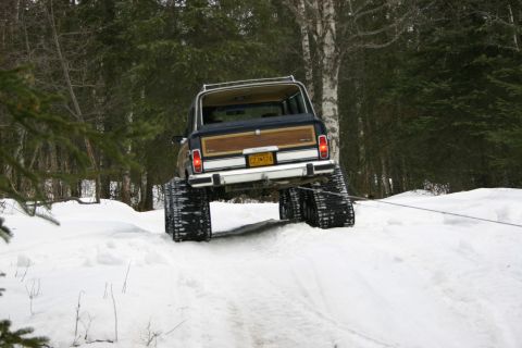 2003 Jeep TJ - Jeep Grand Wagoneer equipped with snow tracks navigates a snowy trail.