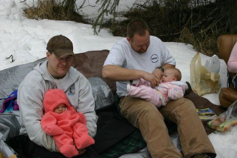2003 Jeep TJ - Two men and two babies are sitting on the snow, possibly on a camping trip.