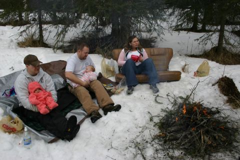 2003 Jeep TJ - A group of people, including two babies, gather around a campfire in a snowy wooded area.