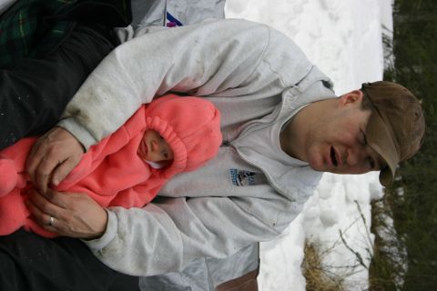 2003 Jeep TJ - A man and a baby are resting in the snow, bundled up against the cold.