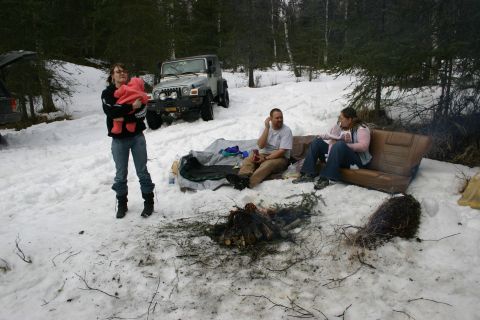 2003 Jeep TJ - A group of people are enjoying a campfire in a snowy forest setting with two Jeeps visible in the background.