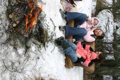 2003 Jeep TJ - A family enjoys a campfire on a snowy day, with two babies bundled in pink outfits.