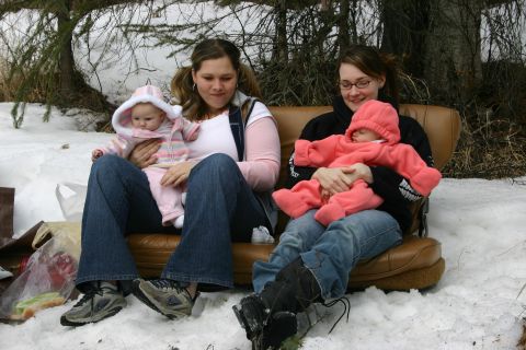 2003 Jeep TJ - Two women and their babies are seated on a couch in a snowy outdoor environment, possibly during winter.