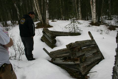 2003 Jeep TJ - A man observes a decaying wooden structure partially buried in snow amidst a birch and pine forest.