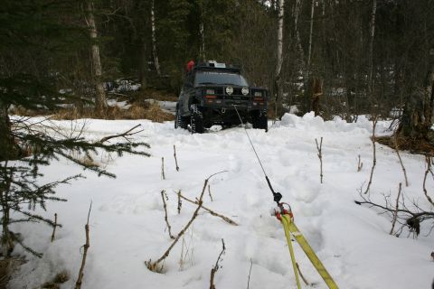 2003 Jeep TJ - A black Jeep TJ is being pulled from deep snow in a wooded area.