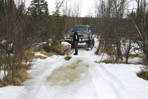 2003 Jeep TJ - A 1980 Ford Bronco equipped with snow tracks navigates a partially frozen trail with two people nearby.