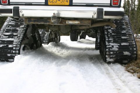 2003 Jeep TJ - A vehicle equipped with snow tracks navigates a snowy trail, leaving deep impressions in the snow.