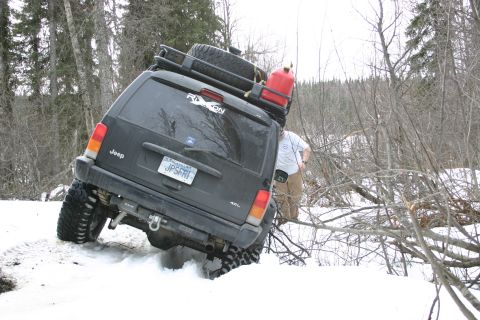 2003 Jeep TJ - Jeep Cherokee XJ with roof rack and gas can navigating snowy terrain.