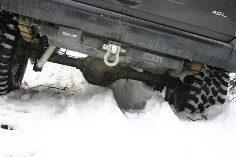 2003 Jeep TJ - The rear undercarriage of a Jeep is visible, with its tires deep in snow and ice.