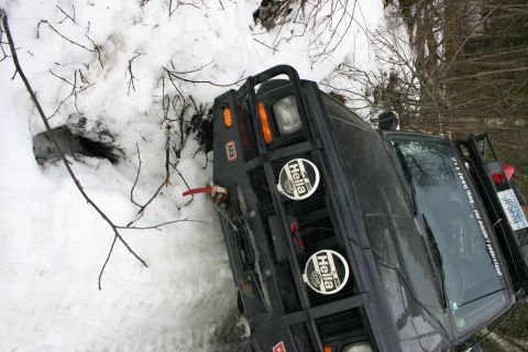 2003 Jeep TJ - A dark 2003 Jeep TJ is partially stuck in snow on a trail, with its front end visible.