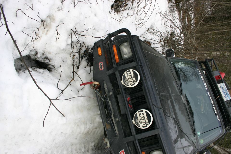 Dark 2003 Jeep TJ with ARB bumper and Hella lights in snow, front 3/4 view
