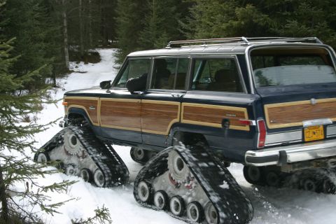 2003 Jeep TJ - A vintage Jeep Grand Wagoneer equipped with snow tracks navigates a wooded path in winter.