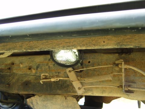1988 Ford Bronco - A rock light is mounted beneath the chassis, attached to the frame and near the vehicle's suspension system offtoading components.
