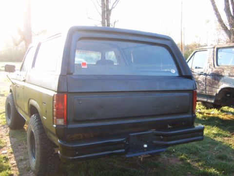 1988 Ford Bronco - The rear of a black Ford Bronco is visible, with another vehicle parked behind it.