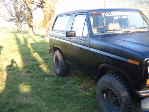 1988 Ford Bronco - This black SUV, likely from the early 1980s, is seen from the side with a banner across the top of the windshield.