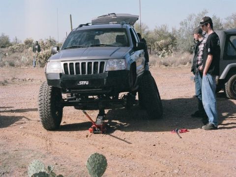 1989 Ford Bronco - Jeep Grand Cherokee undergoing maintenance in a desert environment with another Jeep in the background.
