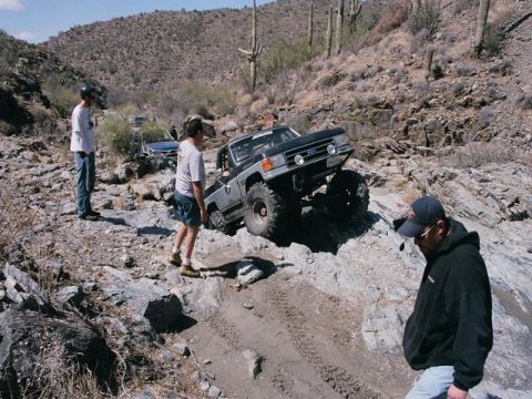 1989 Ford Bronco - A modified Ford Bronco navigates a challenging rocky terrain in a desert environment.