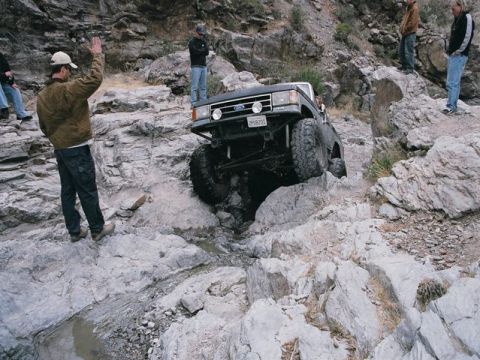 1989 Ford Bronco - Ford Bronco tackles a challenging rocky trail in a desert landscape.