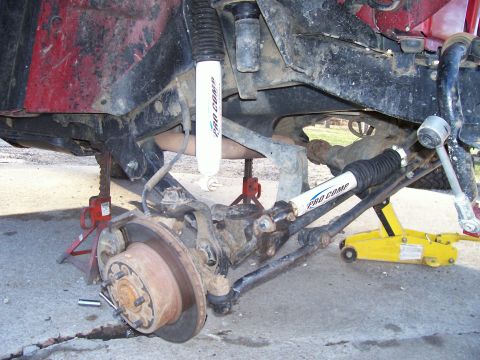 1998 Jeep TJ - The vehicle's suspension and steering system are shown with the wheel removed and supported by jack stands.