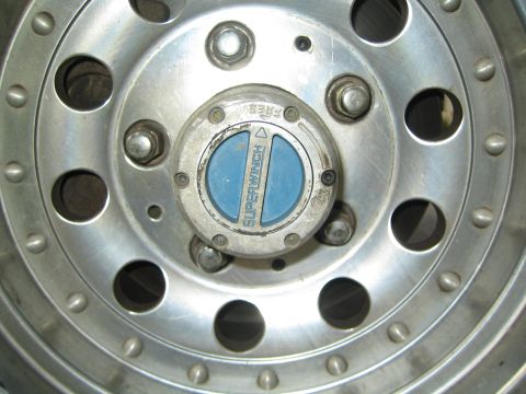 1990 Ford Bronco - Close-up of a polished aluminum wheel with lug nuts and a blue Superwinch locking hub at its center.