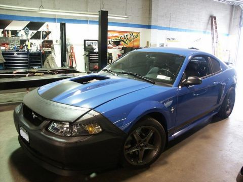 2001 Mercury Grand Marquis - A blue Ford Mustang is parked in a garage, partially covered with a protective car bra.