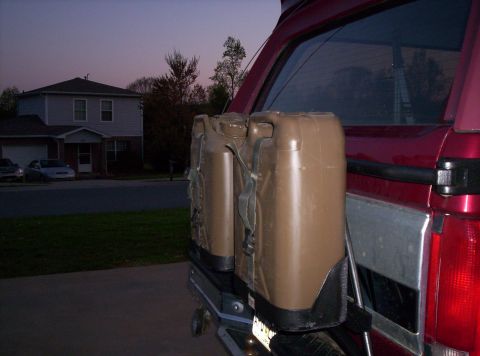 1995 Ford Bronco - Jerry cans attached to the spare tire mount on the back of a vehicle.