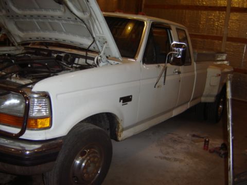 1992 Ford Bronco - This white dually pickup truck is parked inside a garage with its hood open, revealing the engine compartment.