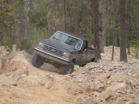 1990 Ford Bronco - Ford Bronco tackling a challenging off-road course with steep inclines and rocks.