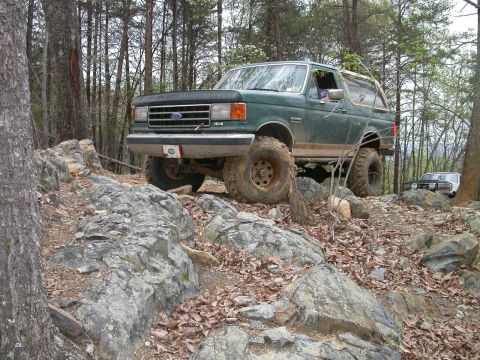 1990 Ford Bronco - This 1990 Ford Bronco navigates a rocky, wooded terrain, its off-road capabilities.