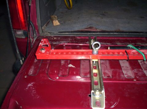 1995 Ford Bronco - A red jack mount is secured inside the cargo area of a red vehicle.