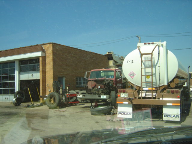 Tanker truck and truck chassis outside a garage