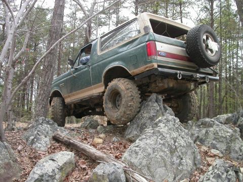 1990 Ford Bronco - This 1990 Ford Bronco is navigating a challenging rocky terrain in a forest.