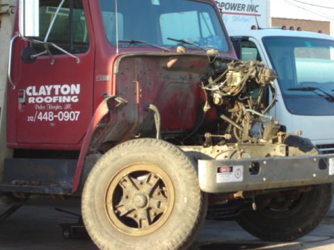 1992 Ford Bronco - A red work truck is parked outside with its engine exposed, showing mechanical components. Another white truck is visible behind it.