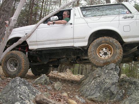 1990 Ford Bronco - A white 1992 Ford Bronco navigates a rocky trail, demonstrating its off-road capabilities.
