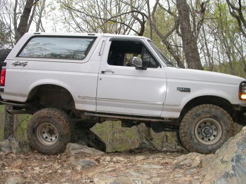 1990 Ford Bronco - This white Ford Bronco is navigating a rocky trail, its off-road capabilities.