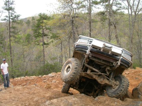 1990 Ford Bronco - A 1990 Ford Bronco navigates a challenging off-road course, tilting precariously on its side.