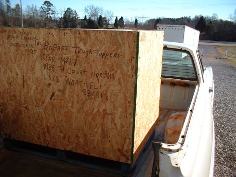 1971 Ford Mustang - A large wooden crate is loaded into the bed of a white pickup truck.