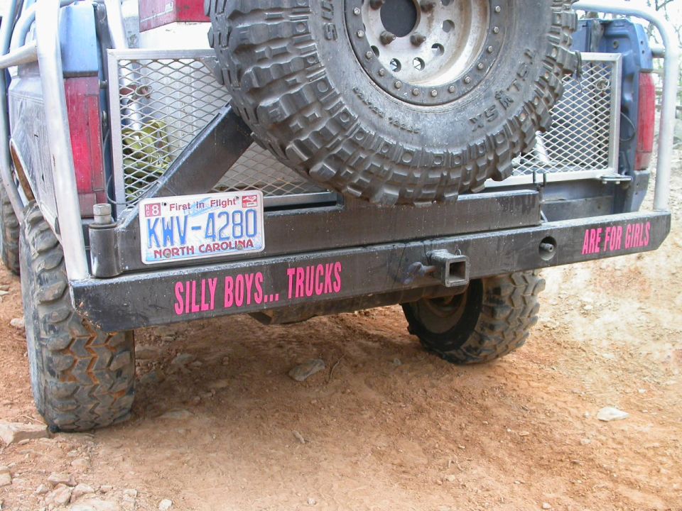 Rear view of a modified truck with a spare tire mounted, North Carolina license plate KWV-4280, and pink text reading 'SILLY BOYS... TRUCKS' and 'ARE FOR GIRLS'