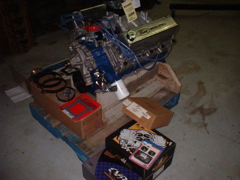 1971 Ford Mustang - A Ford Racing engine is displayed on a pallet with various engine components and boxes.