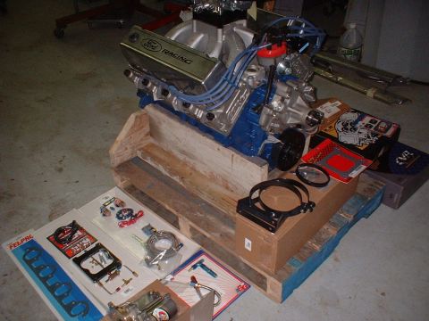 1971 Ford Mustang - Ford Racing engine and various engine parts laid out on a pallet in a garage.