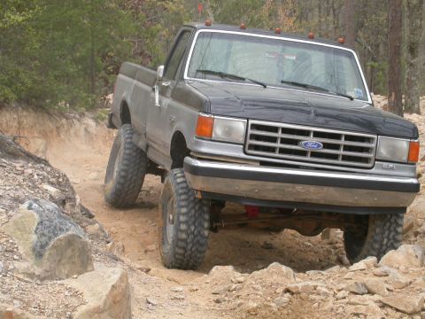 1990 Ford Bronco - Ford F-Series pickup truck with large tires on a challenging off-road course.