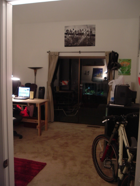 1989 Ford Bronco - A bicycle is parked inside a room next to a desk and a sliding glass door.