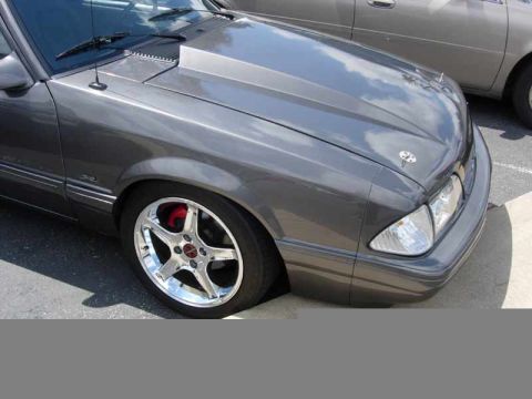 1998 Ford Crown Victoria - Close front-quarter view of a lowered gray Mustang with a chrome five-spoke wheel and red brake caliper.
